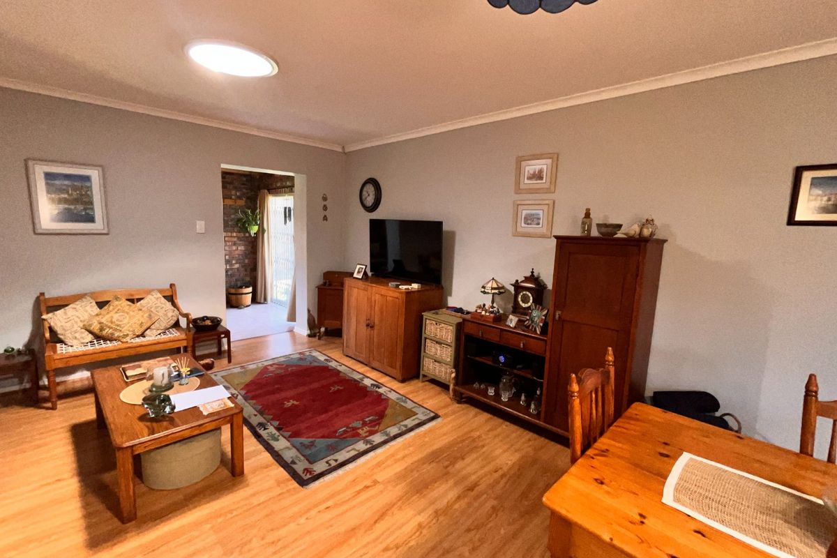 A spacious living room featuring laminate flooring, a coved ceiling, and a skylight, providing a comfortable and functional living area.