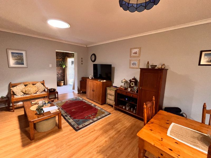 A spacious living room featuring laminate flooring, a coved ceiling, and a skylight, providing a comfortable and functional living area.