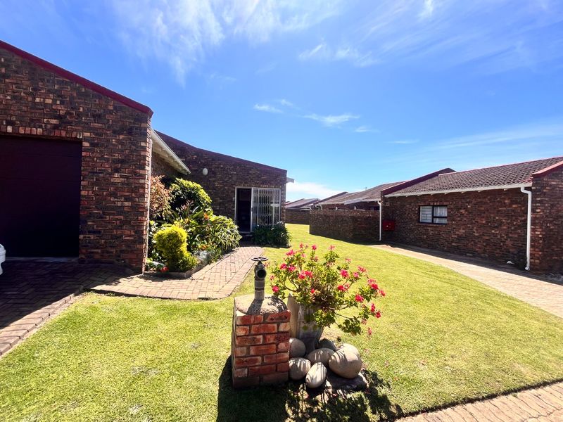 A well-maintained townhouse exterior featuring face brick construction, a paved driveway, and a neat front garden area.