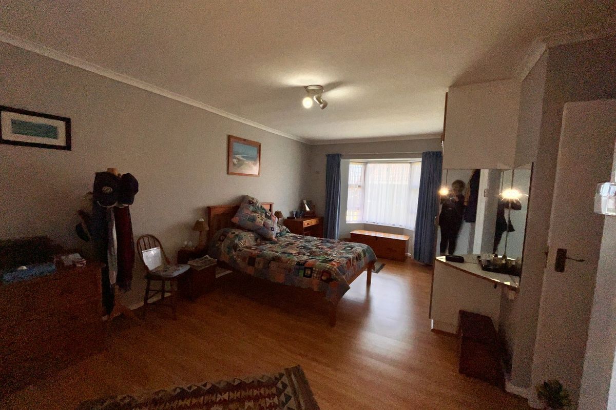 Spacious bedroom featuring laminate flooring, a large bay window providing natural light, and a built-in vanity area with mirror.