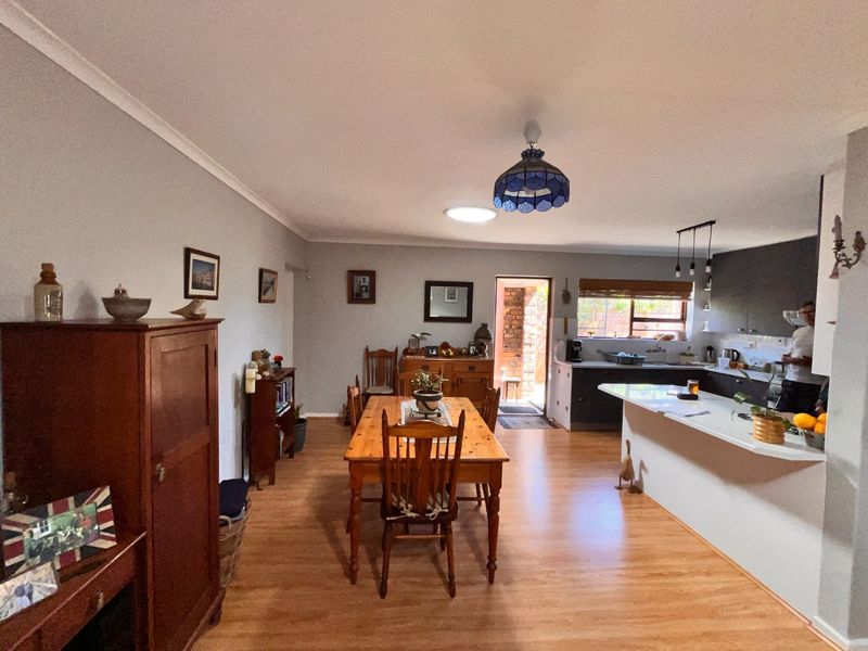 Open plan living and dining area featuring laminate flooring, a functional kitchen with island, and direct access to an outdoor space.