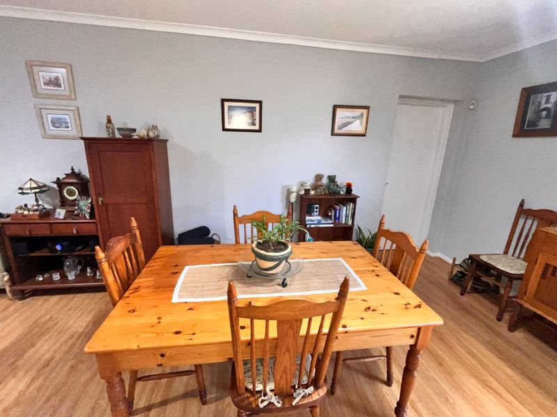 A dining room featuring timber flooring and neutral wall finishes, providing a functional space for family meals.