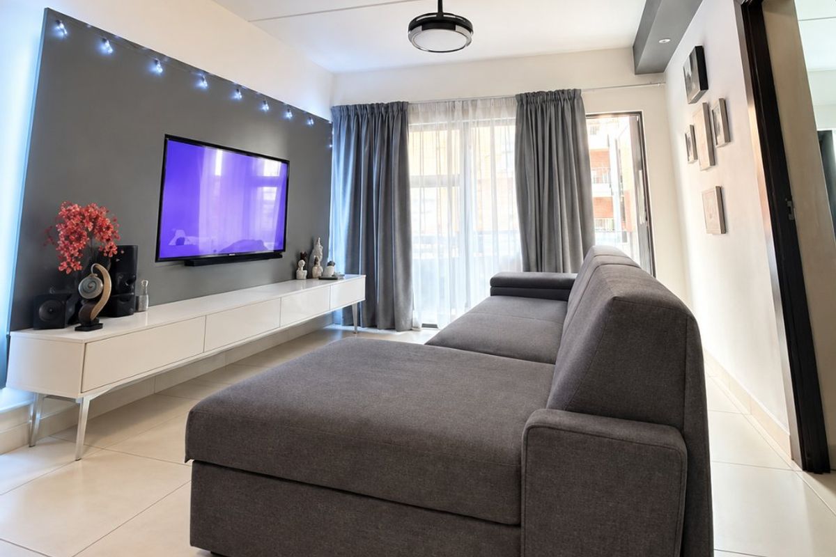 A modern living room featuring tiled flooring, a built-in media console, and recessed ceiling lighting with a central ceiling fan.