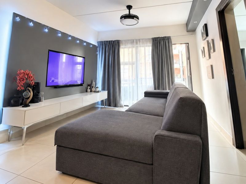 A modern living room featuring tiled flooring, a built-in media console, and recessed ceiling lighting with a central ceiling fan.