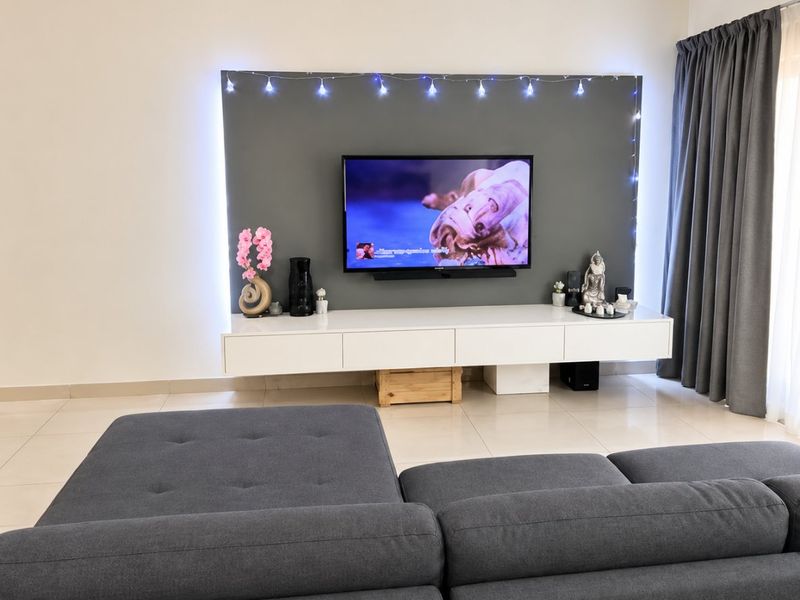 A modern living room featuring a sleek floating media console, a grey feature wall with integrated lighting, and neutral tiled flooring.