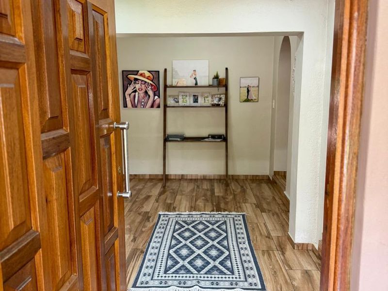 A welcoming entrance hall featuring wood-look tile flooring, a solid wooden door, and a decorative archway leading into the home.