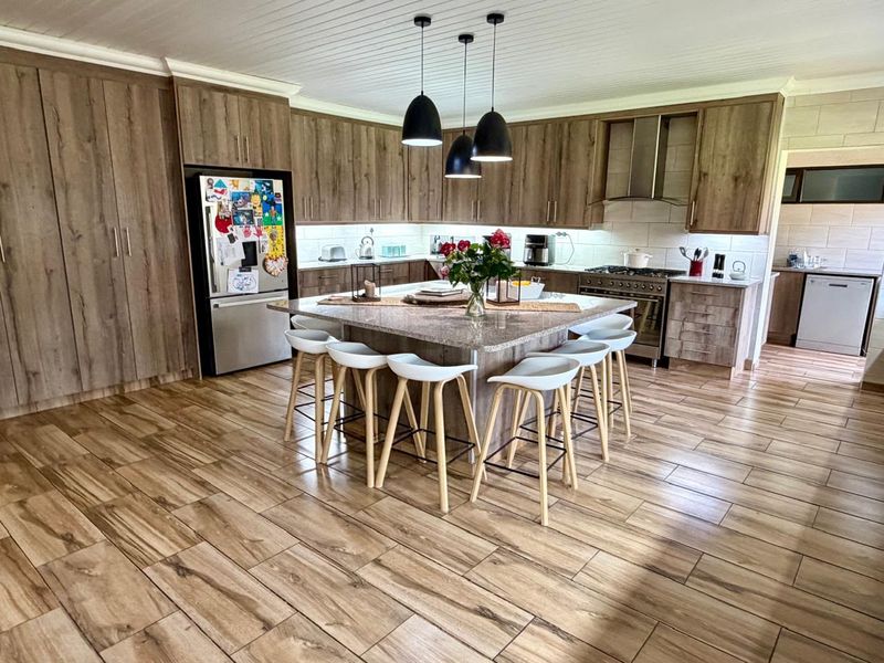 Modern kitchen featuring wood-finish cabinetry, a large central island with granite countertops, gas stove, and stylish pendant lighting.