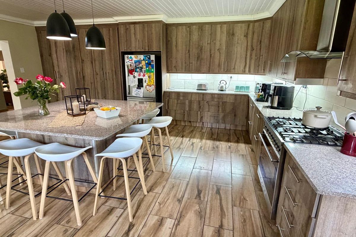 Modern kitchen featuring wood-look cabinetry, granite countertops, a central island with breakfast seating, and high-quality built-in appliances.