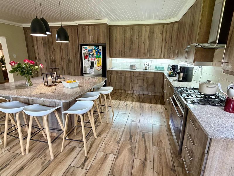 Modern kitchen featuring wood-look cabinetry, granite countertops, a central island with breakfast seating, and high-quality built-in appliances.