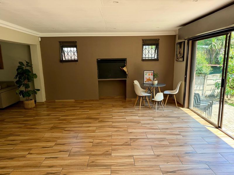 Spacious living area featuring wood-look tiled flooring, a built-in fireplace, and large sliding glass doors providing direct access to the outdoor patio.