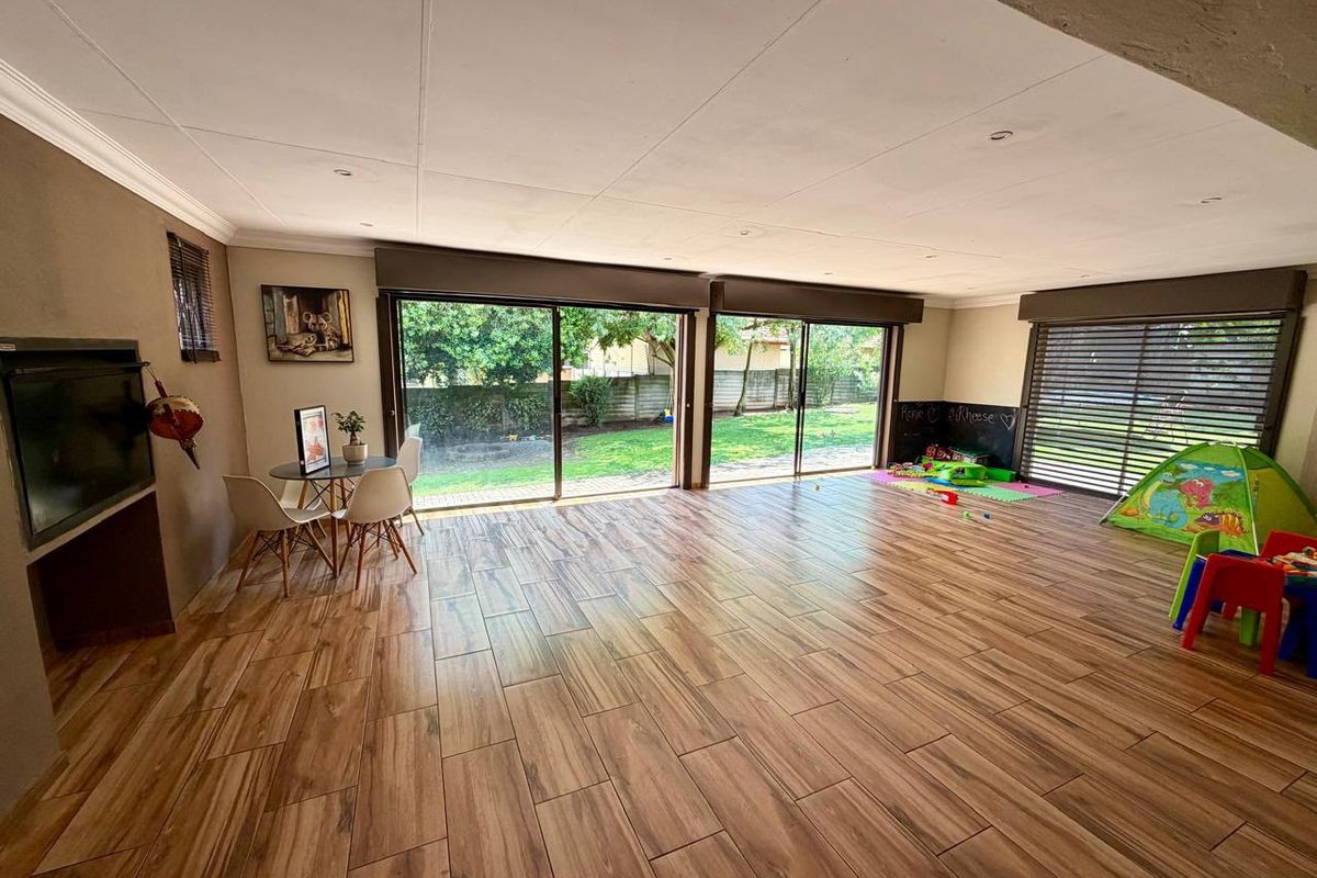Spacious living area featuring wood-look tile flooring, a built-in fireplace, and large sliding glass doors providing direct access to the garden.