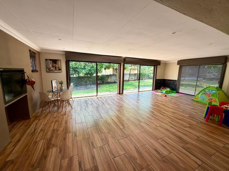 Spacious living area featuring wood-look tile flooring, a built-in fireplace, and large sliding glass doors providing direct access to the garden.