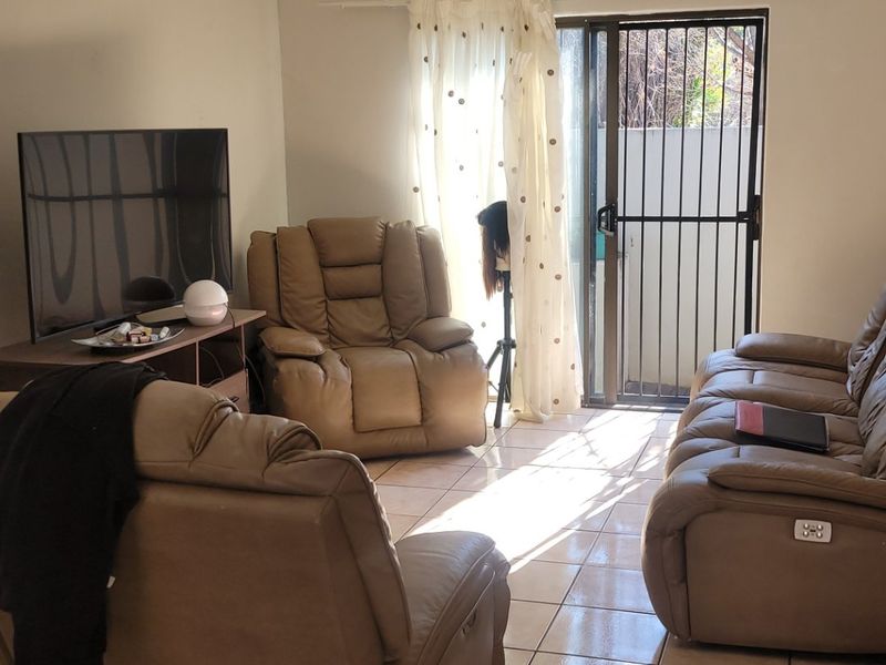 A living room featuring tiled flooring, recessed lighting, and a sliding glass door with a security gate leading to an outdoor area.