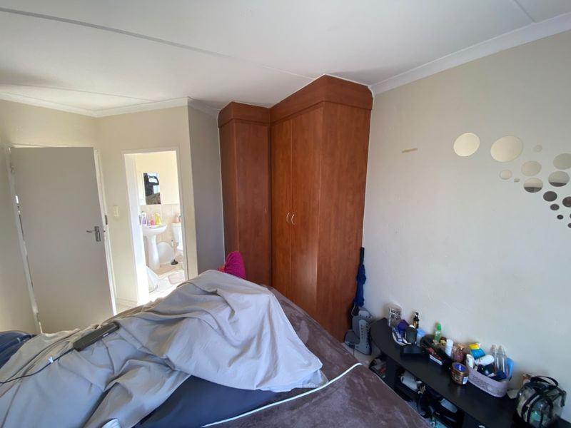 A bedroom featuring a built-in wooden wardrobe and access to an adjoining bathroom.