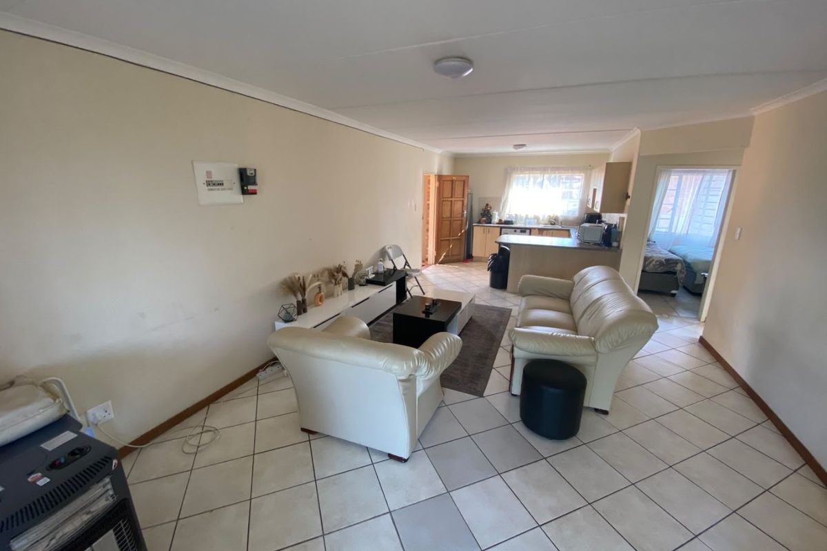 Open plan living area featuring ceramic tiled flooring and a functional kitchen with built-in cabinetry and a breakfast island.