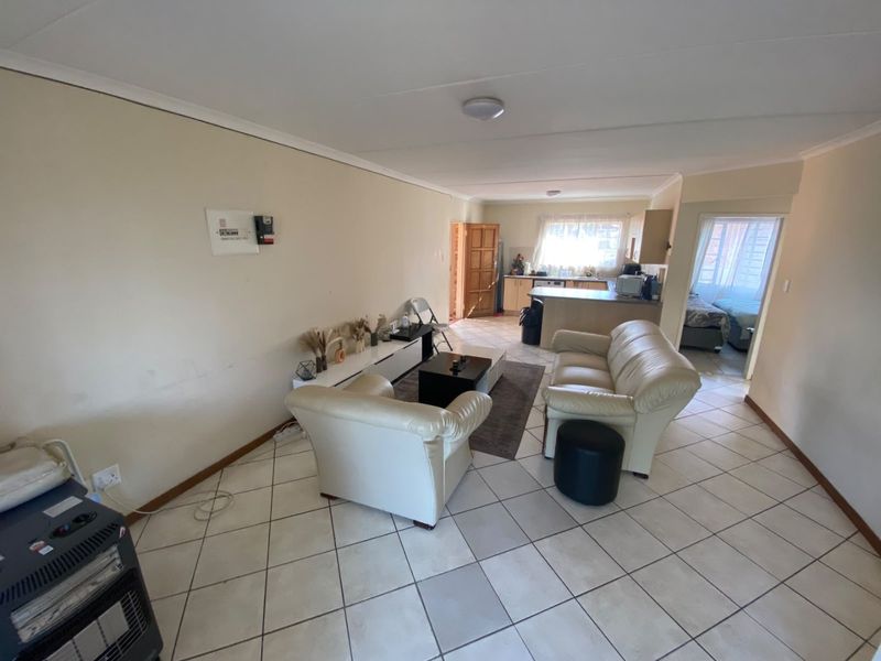 Open plan living area featuring ceramic tiled flooring and a functional kitchen with built-in cabinetry and a breakfast island.
