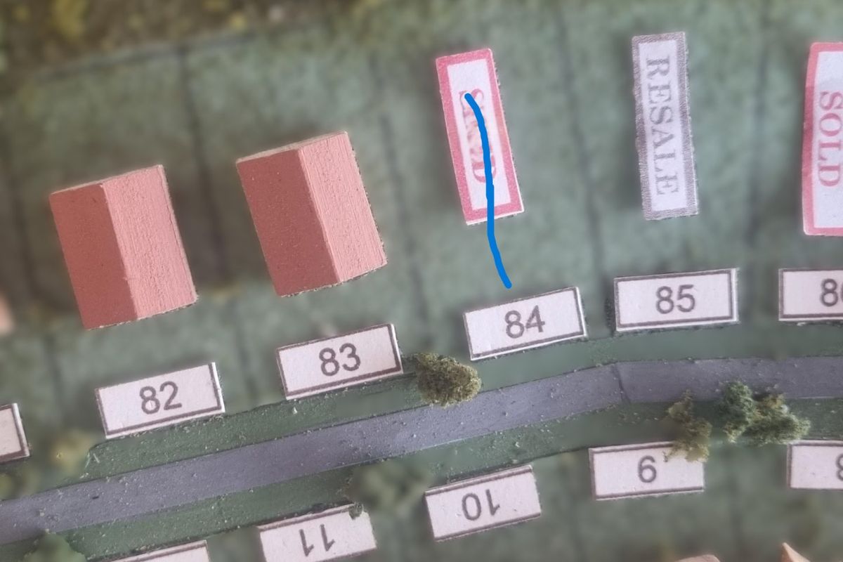 A physical model or map layout showing residential plot number 84 within a development scheme.