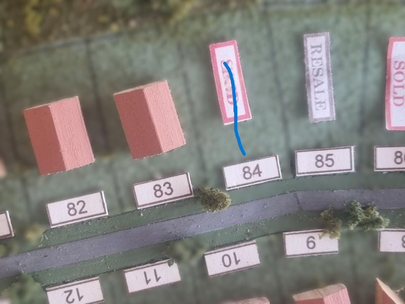 A physical model or map layout showing residential plot number 84 within a development scheme.