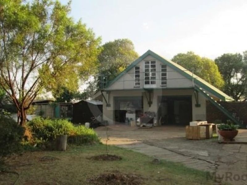 Front view of a commercial property featuring a pitched roof structure, garage bays, and an external staircase set within a landscaped yard.