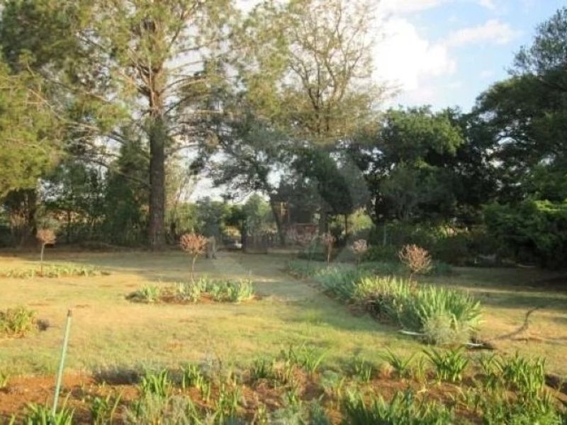 A spacious, established garden area featuring mature trees and landscaped garden beds, offering a peaceful outdoor setting.