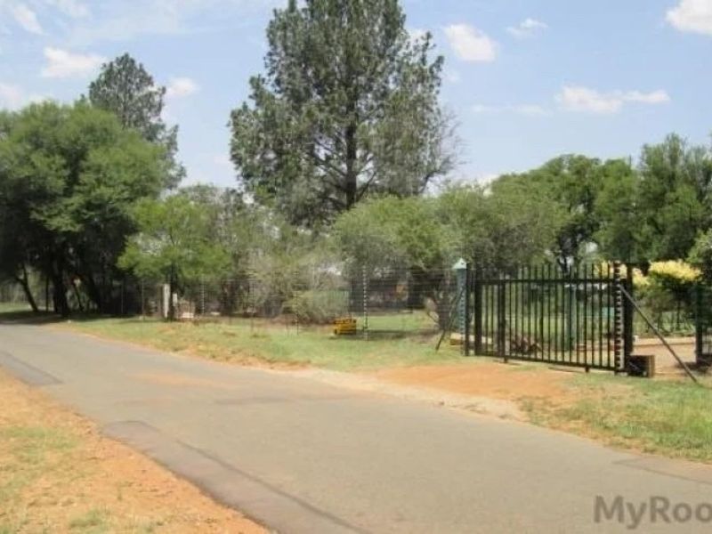 Street view showing the property entrance with a metal security gate and electric fencing along the perimeter.