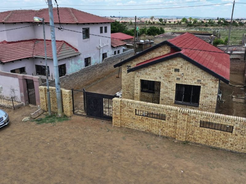Aerial view of a face brick residential property featuring a tiled roof, secure boundary wall, and metal gate access.