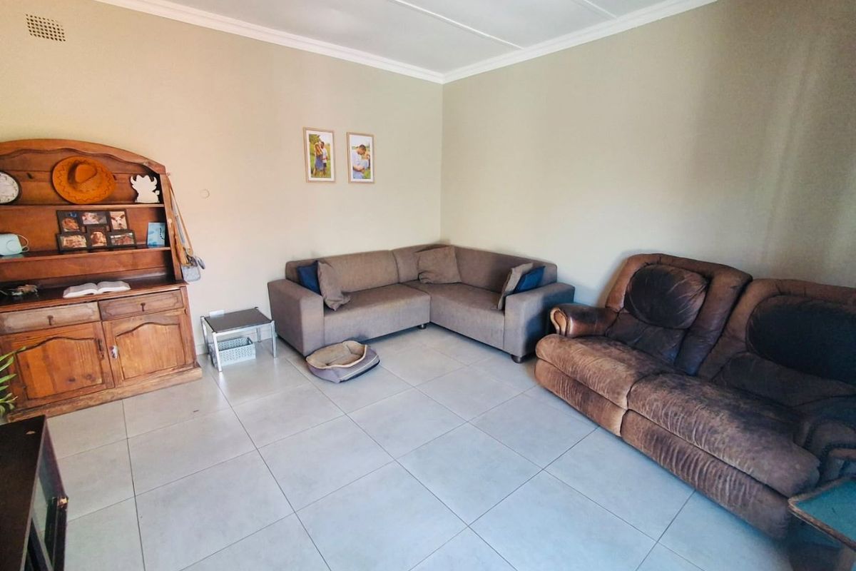 A spacious living room featuring neutral wall tones, large format floor tiles, and classic ceiling cornicing, providing a versatile base for interior updates.