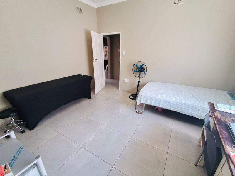 A bedroom featuring neutral wall paint and large format floor tiles, providing a clean and functional space.