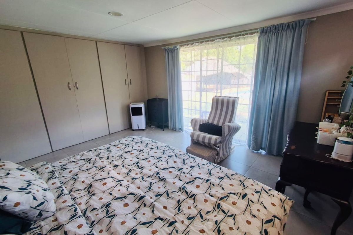 A bedroom featuring built-in cupboards, tiled flooring, and a sliding glass door providing natural light and garden access.