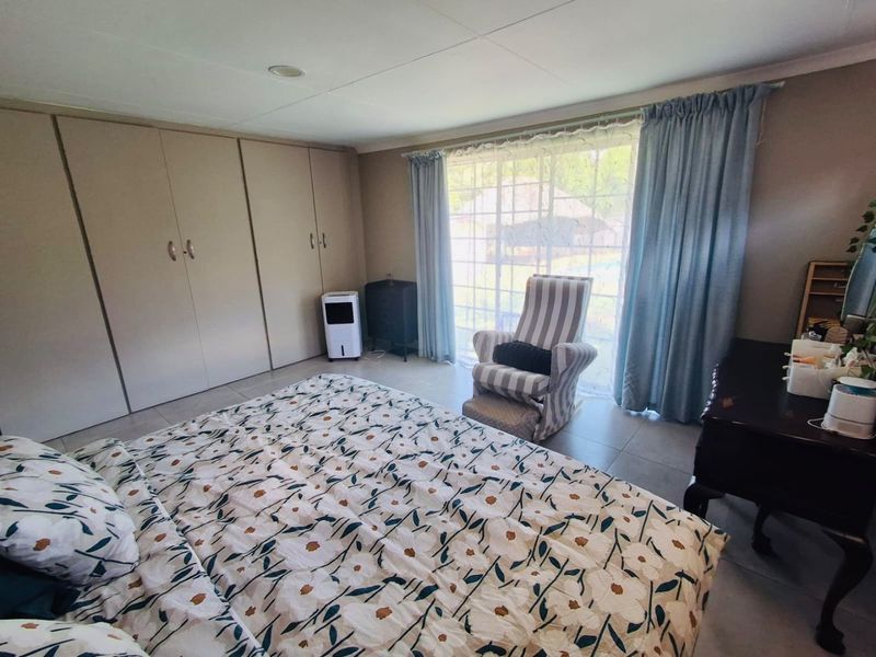 A bedroom featuring built-in cupboards, tiled flooring, and a sliding glass door providing natural light and garden access.