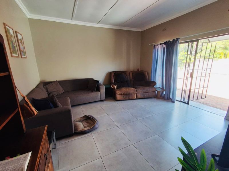 Spacious living room featuring neutral tiled flooring and a sliding glass door providing direct access to the outdoor patio area.