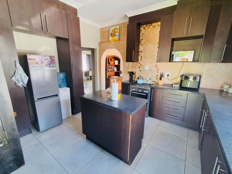 A functional kitchen featuring dark wood cabinetry, granite countertops, a central island, and a tiled backsplash with a gas stove and built-in oven.