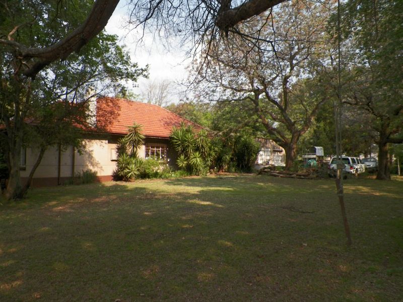 Rear view of the farm property featuring a terracotta tiled roof, brick chimney, and established garden surroundings.