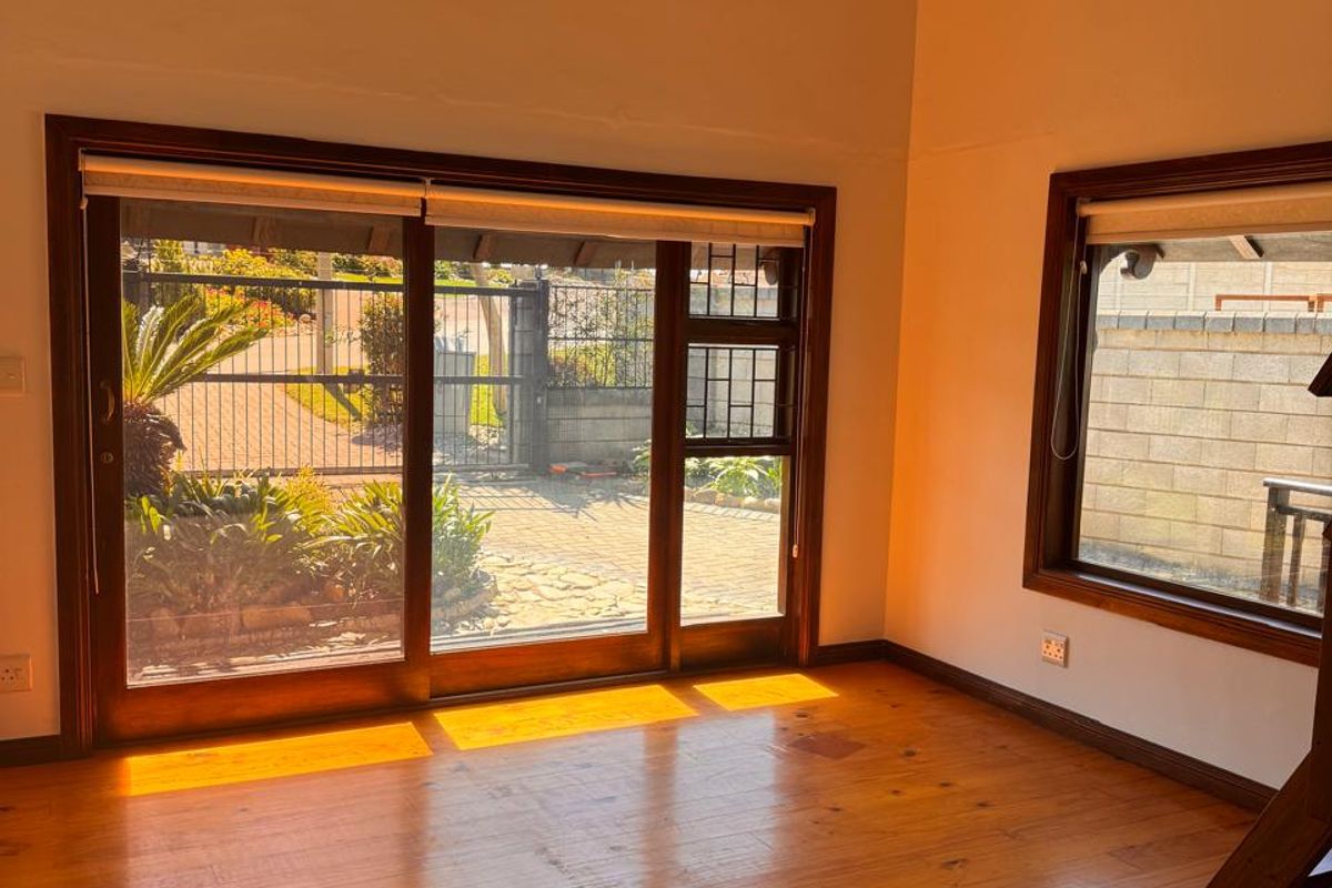 Spacious living area featuring vaulted timber ceilings, polished timber flooring, and large sliding glass doors providing ample natural light and garden access.