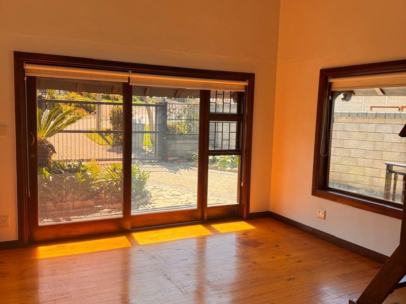 Spacious living area featuring vaulted timber ceilings, polished timber flooring, and large sliding glass doors providing ample natural light and garden access.