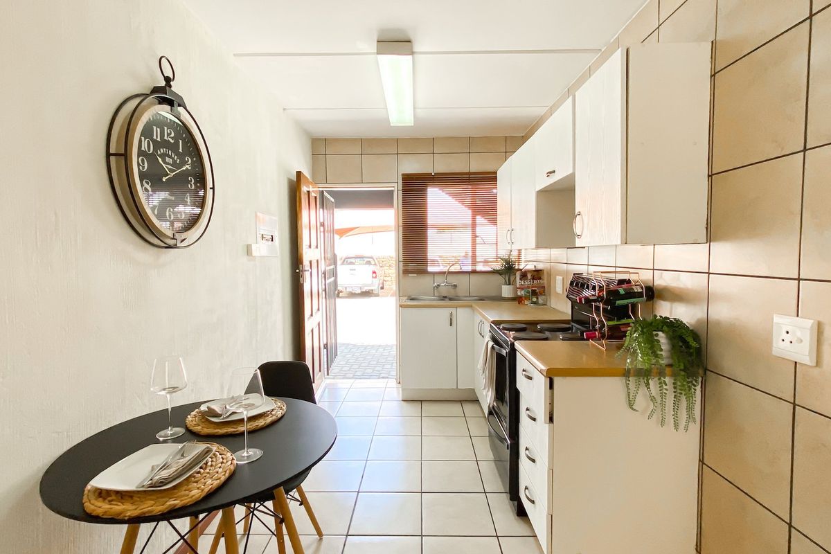 A functional kitchen featuring tiled flooring, built-in cabinetry, a tiled backsplash, and a built-in stove, with direct access to the exterior.