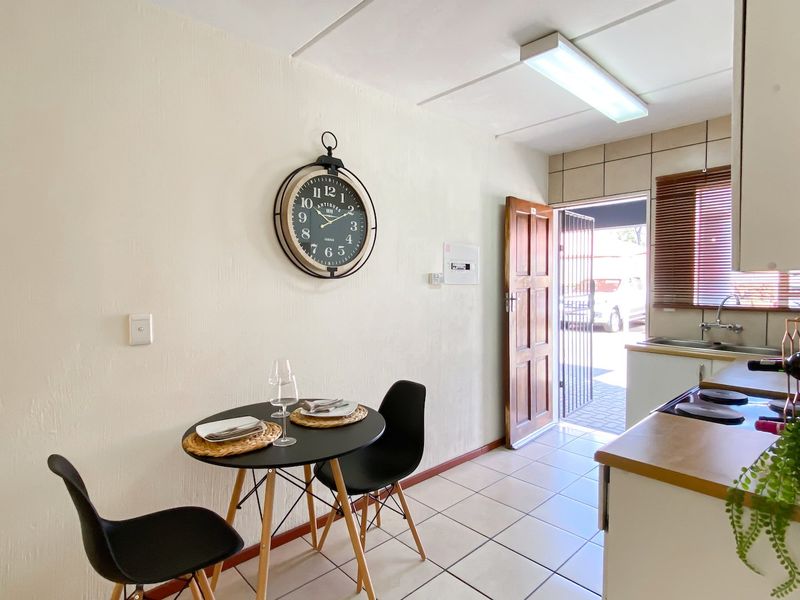 Open-plan kitchen and dining area featuring tiled flooring, functional cabinetry, and direct access to the exterior through a secure entrance door.