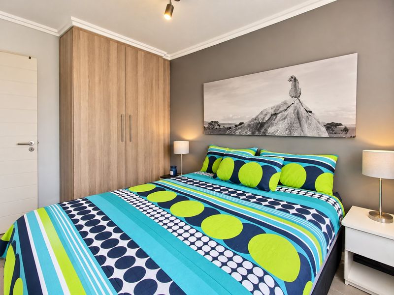 A well-maintained bedroom featuring a large built-in wooden wardrobe, neutral grey walls, and modern ceiling lighting.