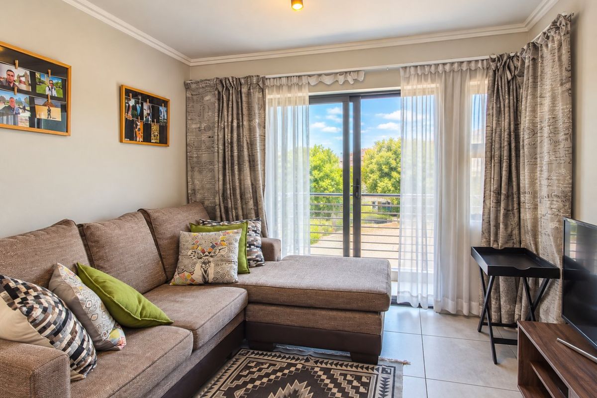 A bright living room featuring tiled flooring and a sliding glass door that provides direct access to a balcony.