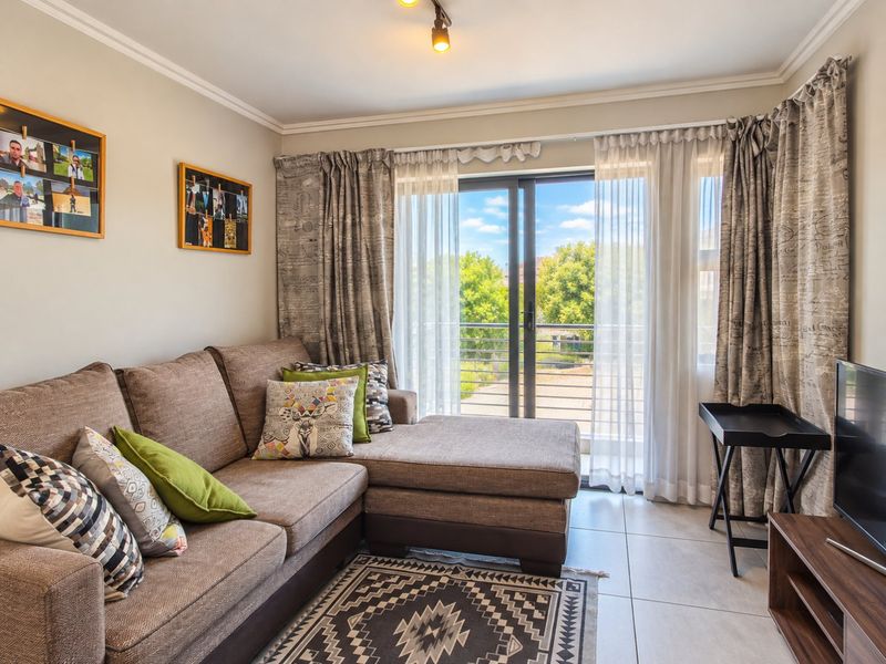 A bright living room featuring tiled flooring and a sliding glass door that provides direct access to a balcony.