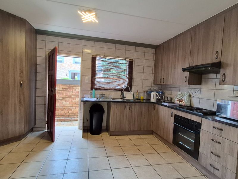 A functional kitchen featuring wood-look cabinetry, built-in oven and hob, tiled flooring, and direct access to an outdoor area.