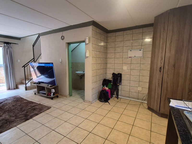 Open plan living area featuring tiled flooring, a staircase, and a built-in cupboard, with direct access to an outdoor patio area.