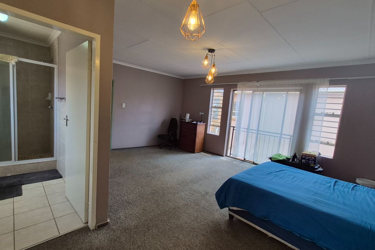 Spacious bedroom featuring an en-suite bathroom, carpeted flooring, and a sliding glass door leading to an outdoor area.