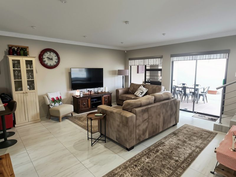 Spacious open-plan living area featuring tiled floors, recessed lighting, and seamless flow to an outdoor patio through large sliding glass doors.