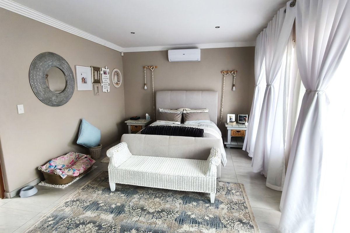 A well-maintained bedroom featuring neutral wall tones, tiled flooring, recessed lighting, and an integrated air conditioning unit.