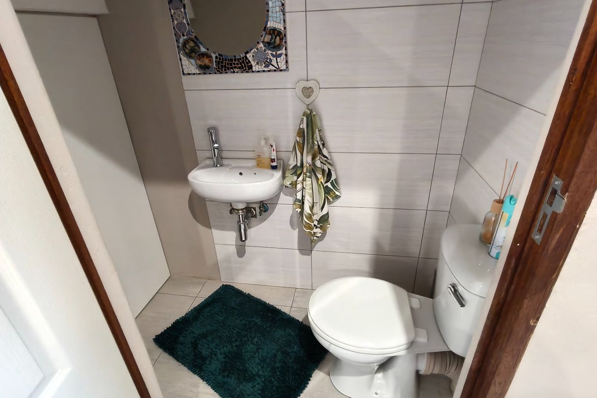 A compact guest bathroom featuring a wall-mounted basin, modern tiled walls, and a standard toilet.