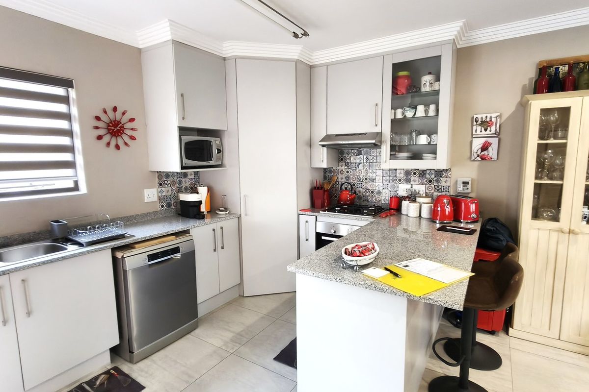 Modern kitchen featuring granite countertops, patterned tile backsplash, built-in appliances, and ample cabinetry, offering a functional and stylish cooking space.