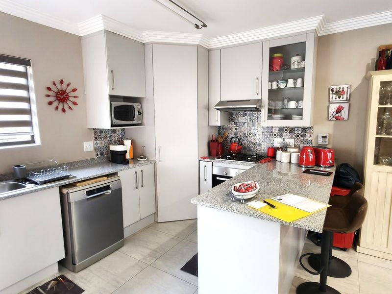 Modern kitchen featuring granite countertops, patterned tile backsplash, built-in appliances, and ample cabinetry, offering a functional and stylish cooking space.