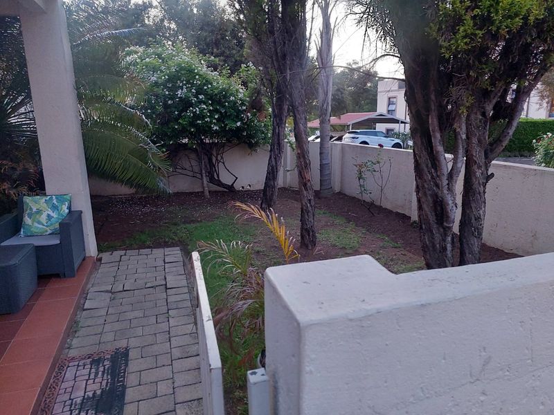 A private rear garden area featuring a paved walkway, tiled patio space, and perimeter boundary walling.