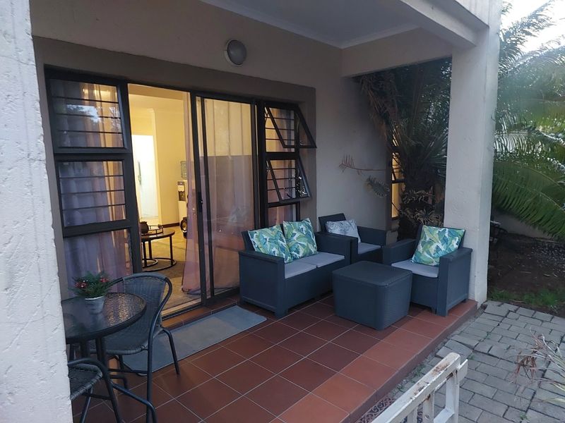 A covered patio area featuring tiled flooring and sliding glass door access to the interior living space.